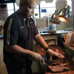 Jamie Bynum, a franchise owner of a Dickey's Barbecue Pit in Lancaster, Calif., slices brisket at his restaurant