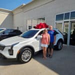 Darin and Mary Davis stand in front of their new 2024 Cadillac XT4 outside Sewell Cadillac