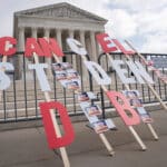 A sign calling for student loan debt relief is seen in front of the Supreme Court