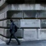 A man passes by the corner stone on the Federal Reserve Bank of New York in the financial district in New York